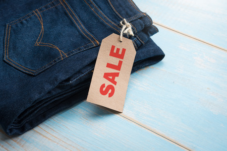 Blue jeans with Sales tag on table woodの写真素材