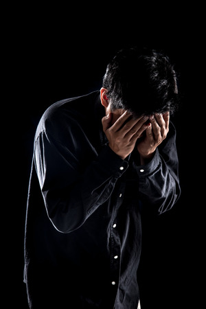 Man suffering from headache against black background,Dramatic portrait of a sadの写真素材