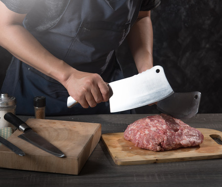 Chef cook cuts large piece of pork meat on wooden cutting board with knife,concept of cookingの写真素材