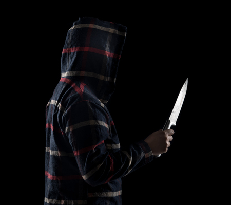Silhouette of dangerous man holding knife against black background