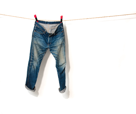 Blue Jeans hanging on a rope clothesline,white backgroundの写真素材