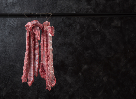 Pork hanging on hook against dark background,pork ripの写真素材