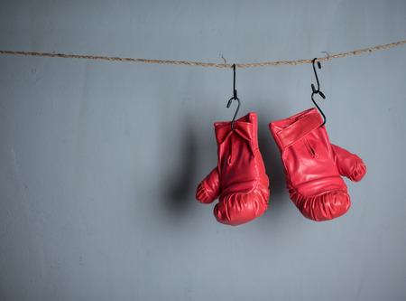 Red boxing mitts hanging on the gray wall.の写真素材