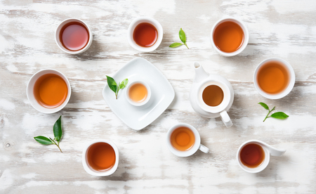 Tea concept,Teapot and cup of herbal tea with green tea leaves on wood,top viewの写真素材