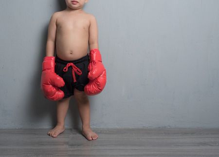Boy in boxing gloves against gray wallの写真素材