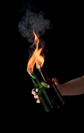 Molotov cocktail bottle with fire in the hand on a black background.の写真素材