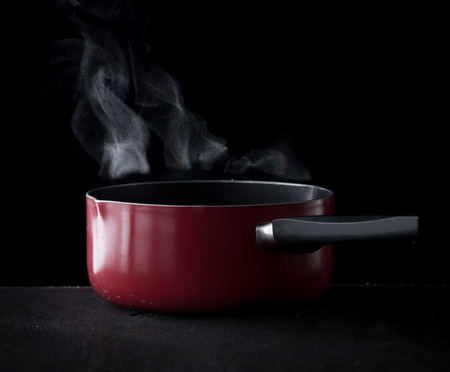 Steaming pot over dark background