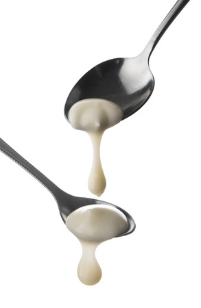 Sour cream in spoon isolated on whiteの写真素材