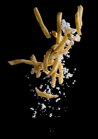 French fries with salt explode flying in the air isolated on blackの写真素材