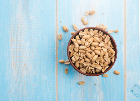 Roasted salted peanuts in wooden bowl on wooden table,top viewの写真素材