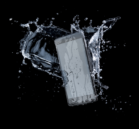 Smartphone with splashing of water or explosion flying in the air isolated on blackの写真素材