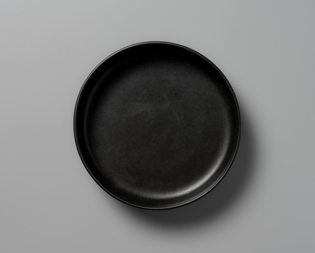 Top view empty black plate on grey background with shadowの写真素材