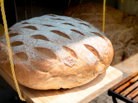 Loaf of bread is hanging on wooden shelf in bakery