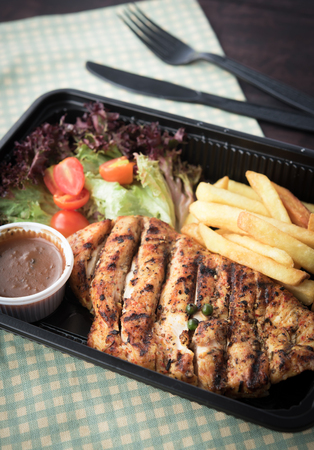 Chicken steak with french fries and sauces in plastic boxの写真素材