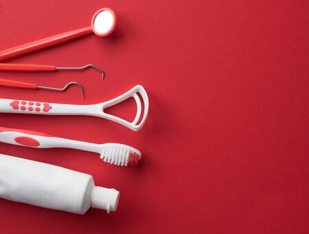 Set of different tools with toothbrushes and toothpaste tube against red background,dental care