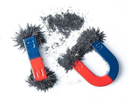 Horseshoe magnet and bar magnet attracting iron powder on white backgroundの写真素材
