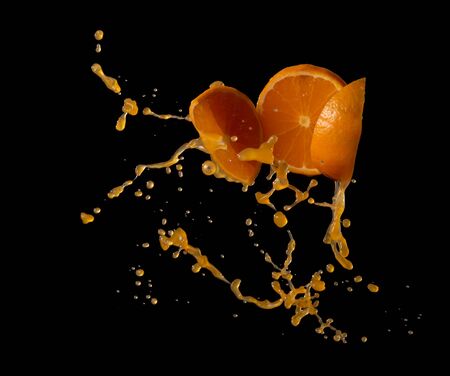 Orange juice with orange fruit slices splash or explosion flying in the air isolated on black backgroundの写真素材