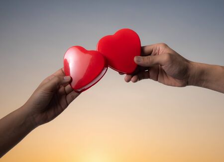 Female and man's hands with red heart at sunsetの写真素材