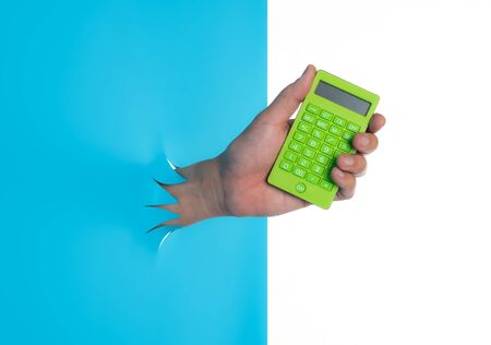 Man holding and showing calculator through the torn blue plastic isolated on white backgroundの写真素材