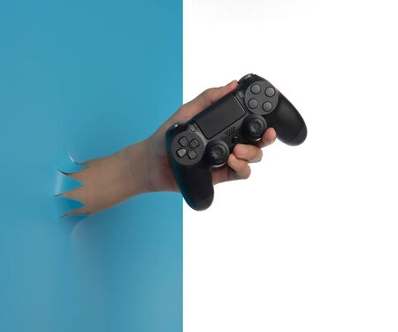 Gaming concept,Hand hold new joystick through the torn blue plastic isolated on white background