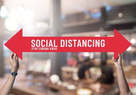 Social distancing,holding sign with message about social distancing ,Space between people to avoid spreading COVID-19 Virus in restaurant,New normalの写真素材