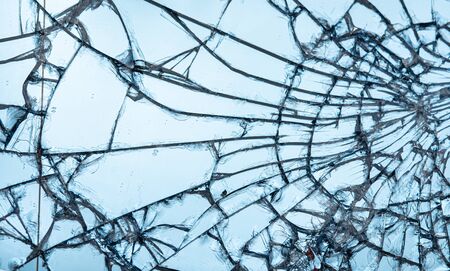 Broken glass texture close up on blue background