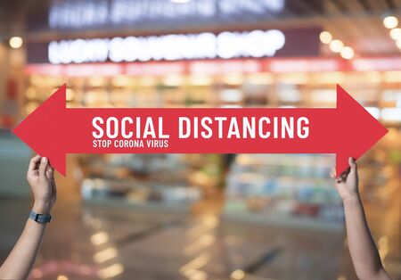 Social distancing,holding sign with message about social distancing ,Space between people to avoid spreading COVID-19 Virus at supermarket store,New normalの写真素材