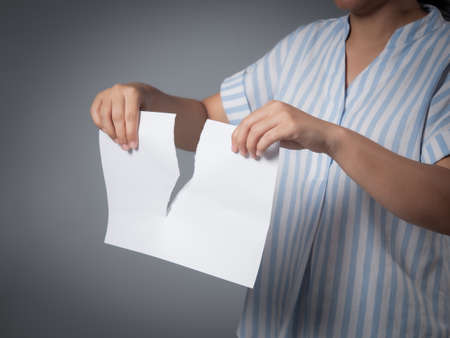 Woman tears white piece of paper against on gray backgroundの写真素材