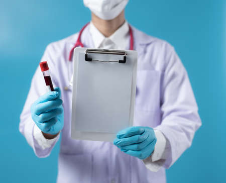 Doctor showing clipboard with blank sheet of paper and tube of blood, you can place your text in copy spaceの写真素材
