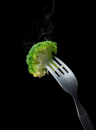 Fork with boiled broccoli on black backgroundの写真素材