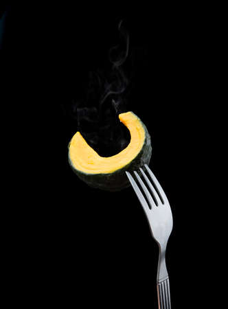 Fork with slices of boiled fresh pumpkin on black backgroundの写真素材