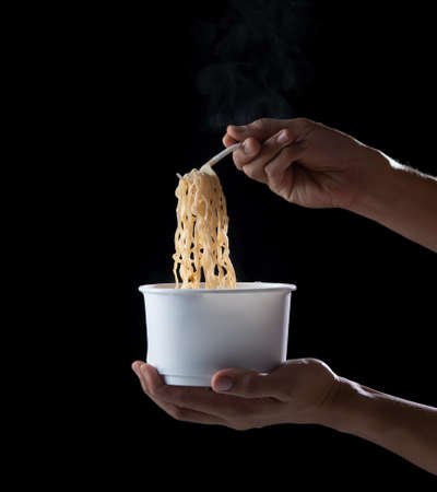 Bowl of instant noodles plastic fork on dark background, fast food serviceの写真素材