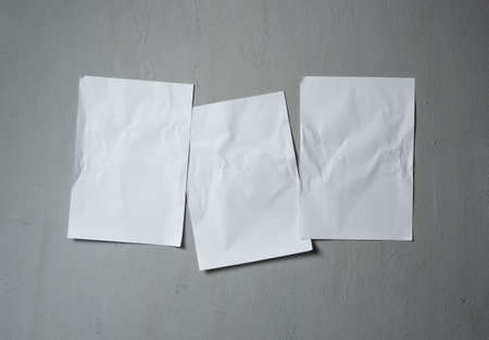 Empty old wrinkled white A4 paper stick on gray cement wall, changeable background. white paper note on grayの写真素材