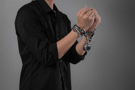 Arrest the offender,Male hands with chains and key around the wrists on a gray background