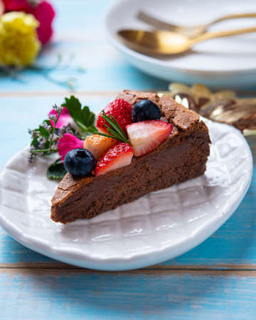 Portion of sliced chocolate brownie cake dessert with strawberries and blueberries
