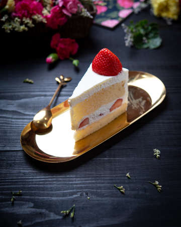 Portion of sliced cake with cream and strawberries