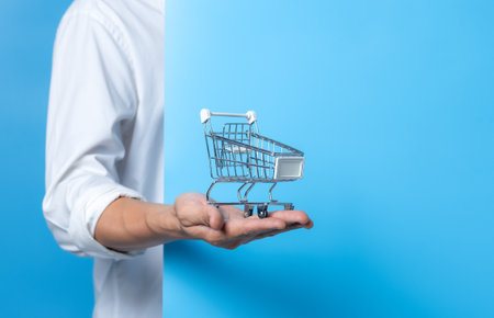 Man holding shopping cart on blue background,copy space for textの写真素材