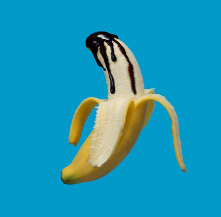 Banana poured with liquid chocolate on blue background close upの写真素材