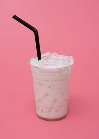 Ice milk in plastic cup on pink backgroundの写真素材
