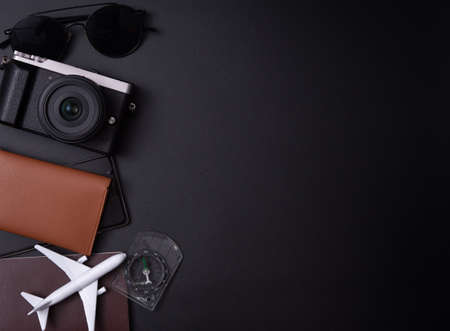 Travel concept:Top view photo of sunglasses compass camera and plane model on passport cover on dark...