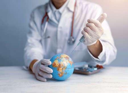 Doctor's hands in medical surgical gloves injecitng vaccine into the earth,Concept the world's fight...