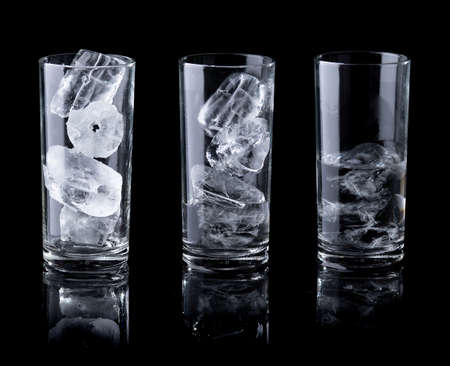 Melting ice in clear glass isolated on blackの写真素材