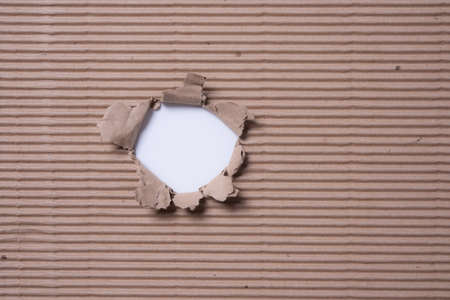 Ripped hole in corrugated cardboard or brown paper box sheet texture for backgroundの写真素材