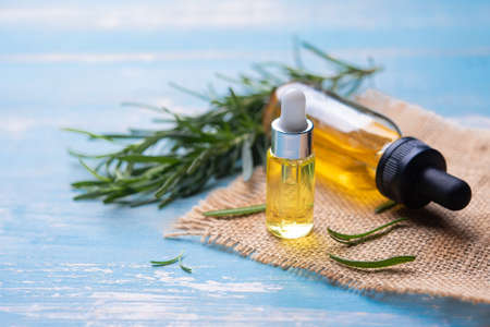 Bottle of essential oil with fresh rosemary twigs on wood backgroundの写真素材