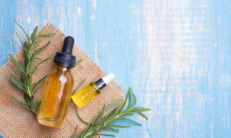 Bottle of essential oil with fresh rosemary twigs on wood backgroundの写真素材