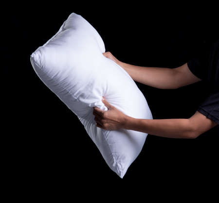 Man holding big pile of white soft pillows on black backgroundの写真素材