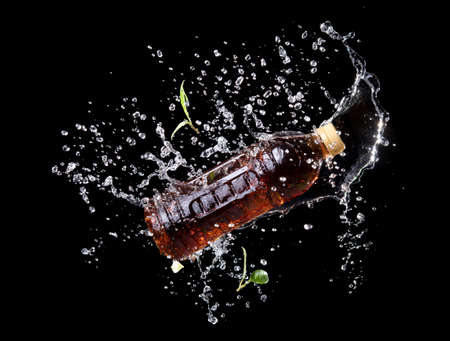 Bottle of ice tea with water splash on black background