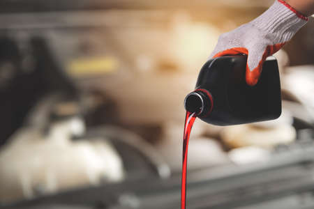 Hand mechanic in repairing car,Pouring oil to car engine on engine backgroundの写真素材