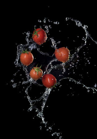 Fresh red Tomatoes in splash of water Isolated on black backgroundの写真素材