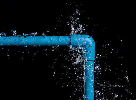 leaked and splash water from pvc plastic pipe over a black background.の写真素材